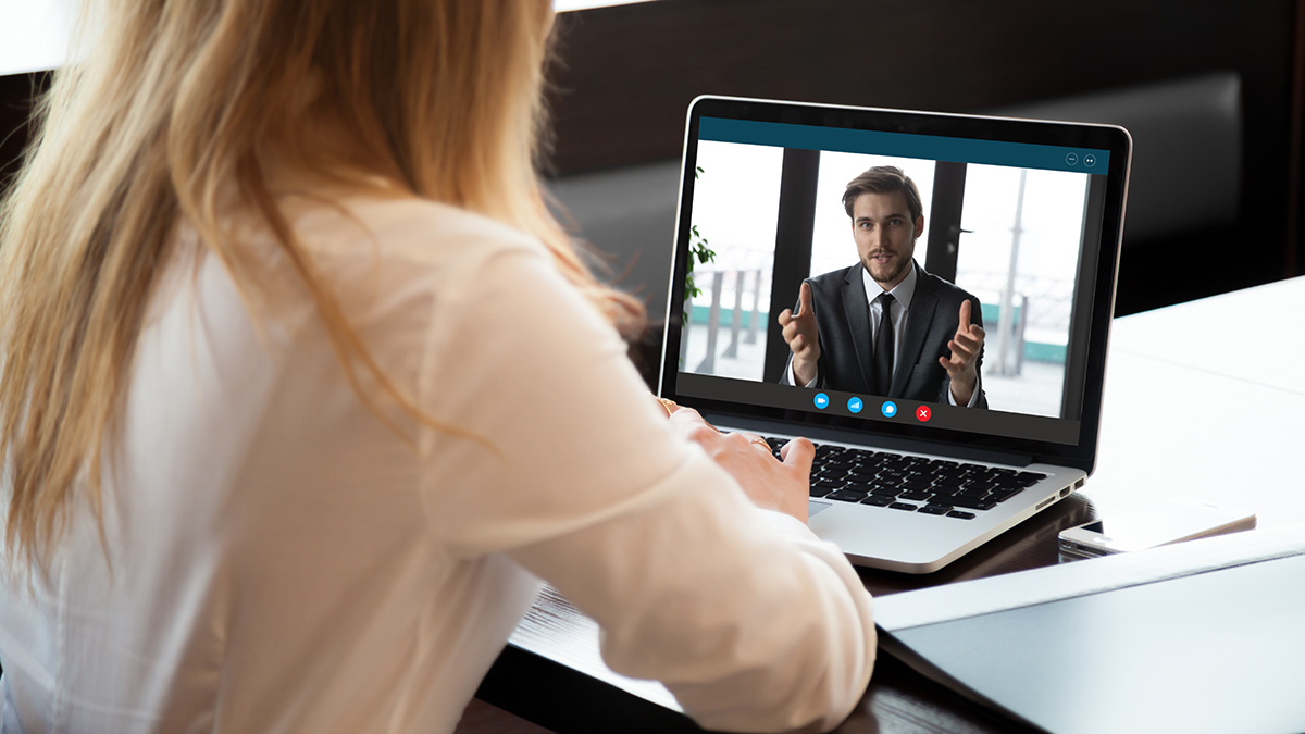 Vrouwelijke medewerker woont informatiebijeenkomst over toetsingen digitaal bij via een laptop